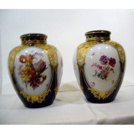 Pair of KPM cobalt and flowered urns, each with 4 cartouches of flowers