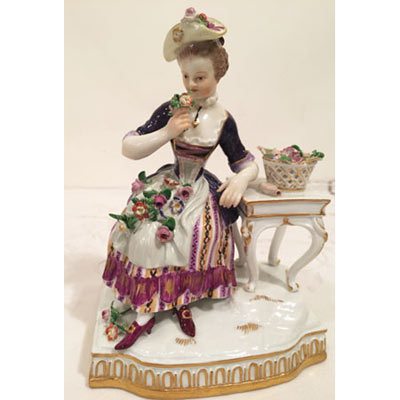 Meissen figurine of lady smelling flowers representing the sense of smell.