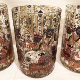 Close up of a set of six hand painted tumblers with paintings of men on horse back.