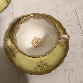 Inside of yellow Meissen cup and saucer with paintings of lovers