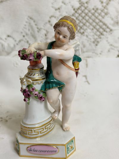Meissen Cherub Figurine who is Holding Two Hearts Together on a Pedestal