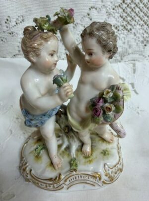 Meissen figural group of a boy holding a cornucopia full of flowers and a garland with a girl holding a flower bouquet.