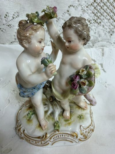Meissen figural group of a boy holding a cornucopia full of flowers and a garland with a girl holding a flower bouquet.